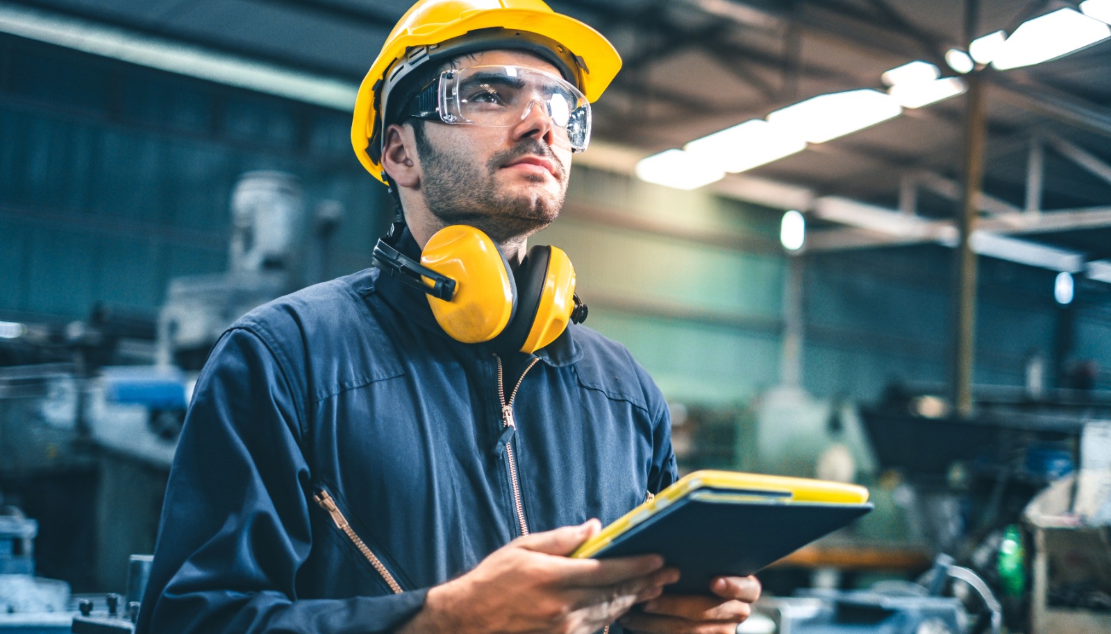 Engenheiro programando CLP Siemens no TIA Portal em ambiente industrial com painel elétrico aberto e sistema de automação em operação